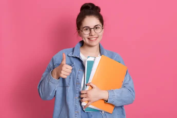 a girl holding some orange and blue notebook and showing thumps up